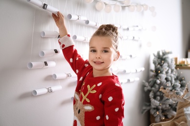 Little girl taking gift from New Year advent calendar at home