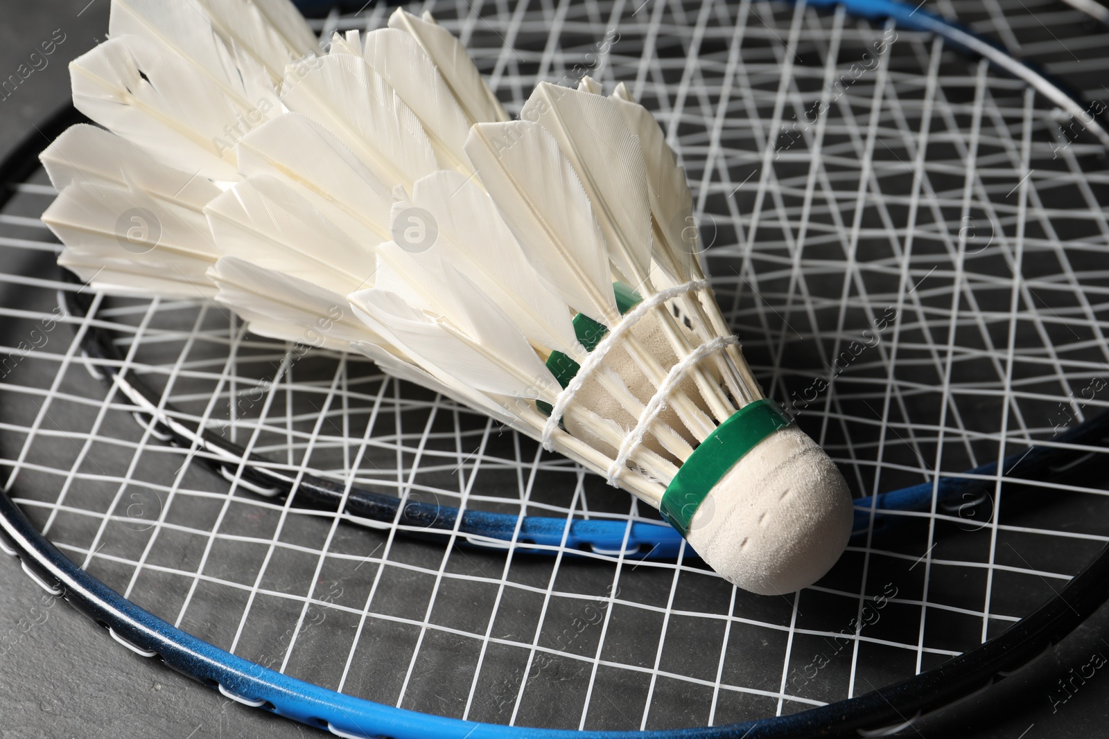 Photo of Feather badminton shuttlecocks and rackets on grey background, closeup