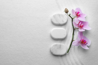 Photo of Flat lay composition of white stones and flowers on sand with pattern, space for text. Zen, meditation, harmony