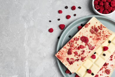 Photo of White chocolate bars with freeze dried fruits on grey marble table, flat lay. Space for text