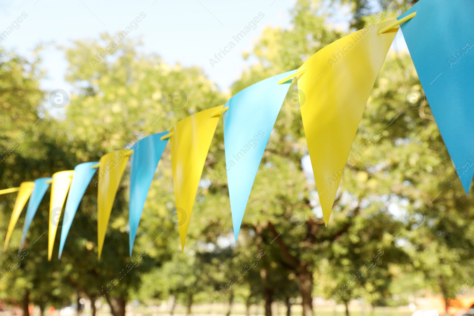 Photo of Colorful bunting flags in park. Party decor