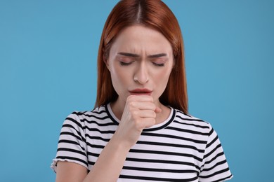 Photo of Woman coughing on light blue background. Cold symptoms