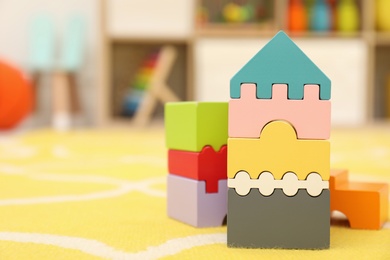 Photo of Wooden castle made of colorful blocks on carpet in playroom, space for text. Interior design