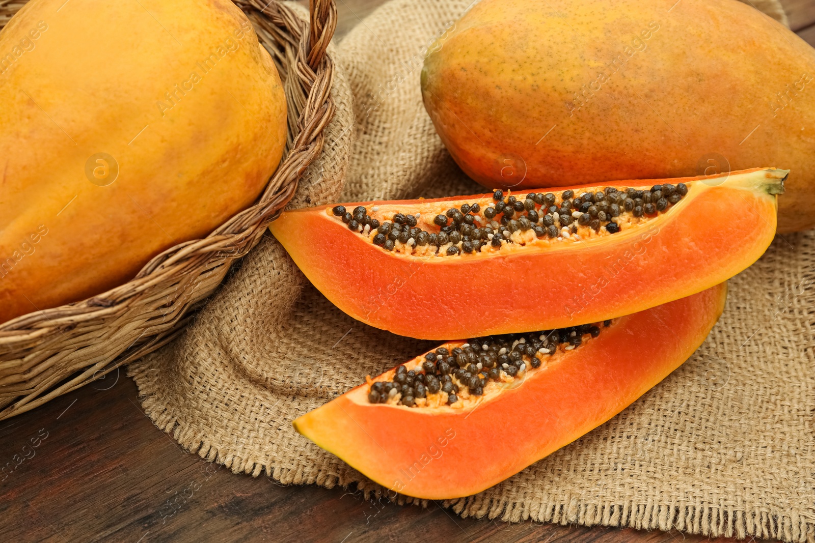 Photo of Tasty whole and cut papaya fruits on wooden table, above view