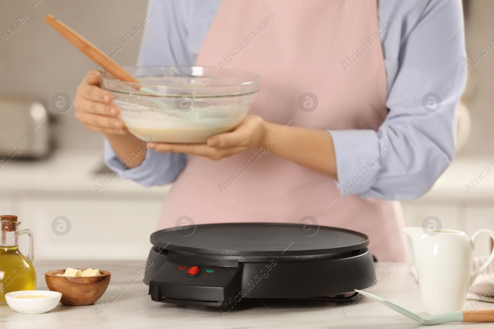 Photo of Woman cooking delicious crepes in kitchen, closeup