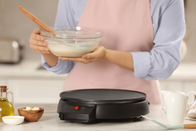 Woman cooking delicious crepes in kitchen, closeup