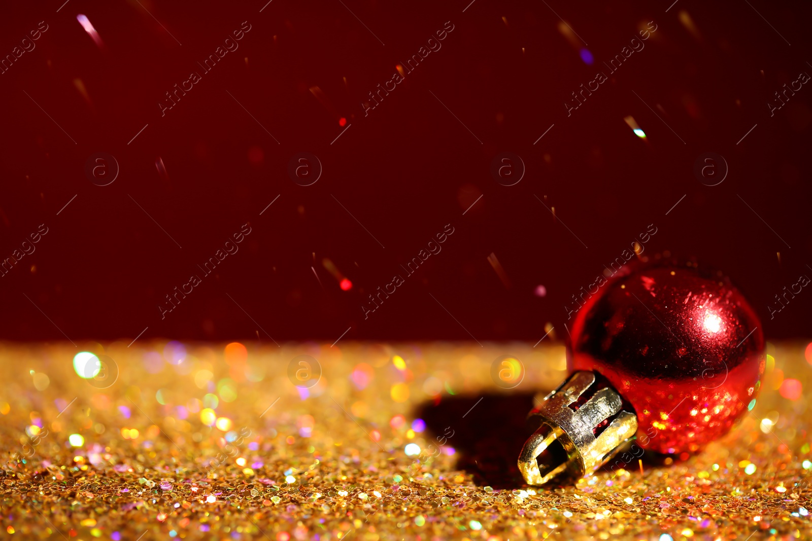 Photo of Golden paillettes and Christmas ball against color background. Space for text