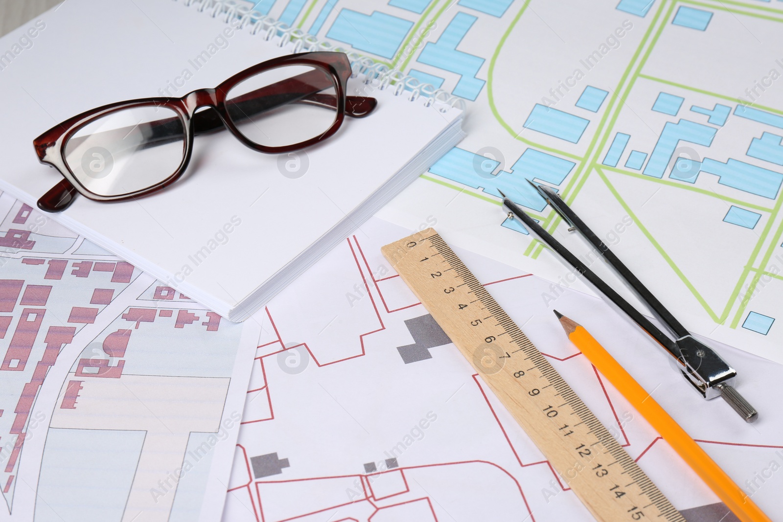 Photo of Office stationery and eyeglasses on cadastral maps of territory with buildings