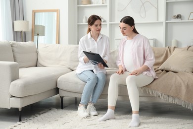 Photo of Doula working with pregnant woman on sofa at home. Preparation for child birth