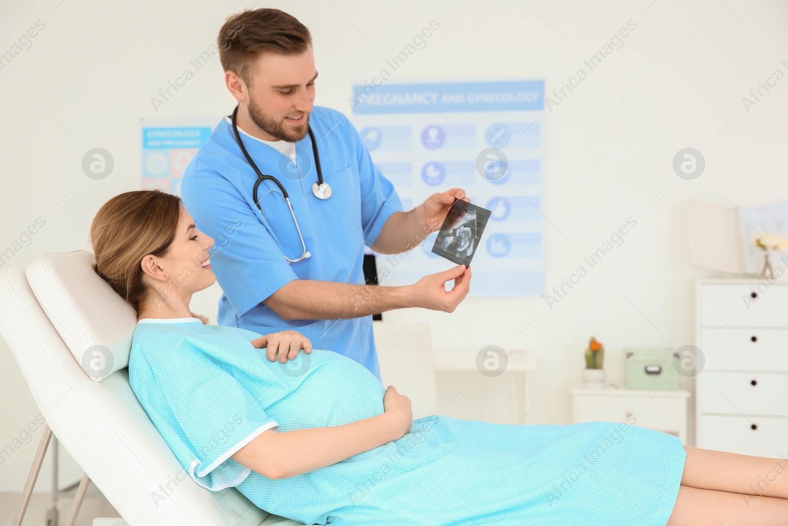 Photo of Gynecology consultation. Doctor showing ultrasound to pregnant woman in clinic