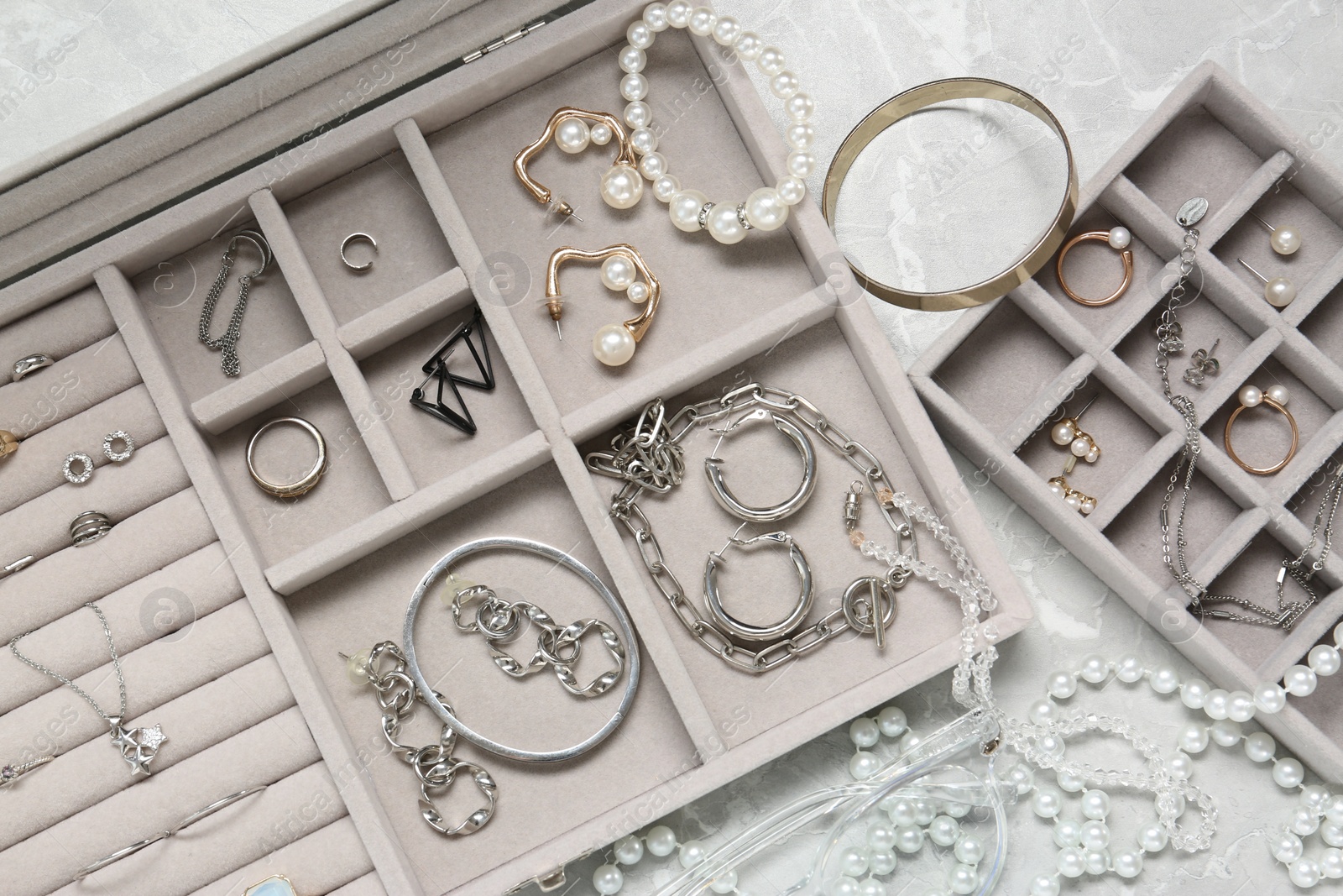 Photo of Jewelry boxes with many different accessories on light grey table, flat lay