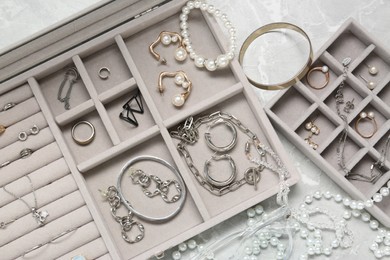 Jewelry boxes with many different accessories on light grey table, flat lay