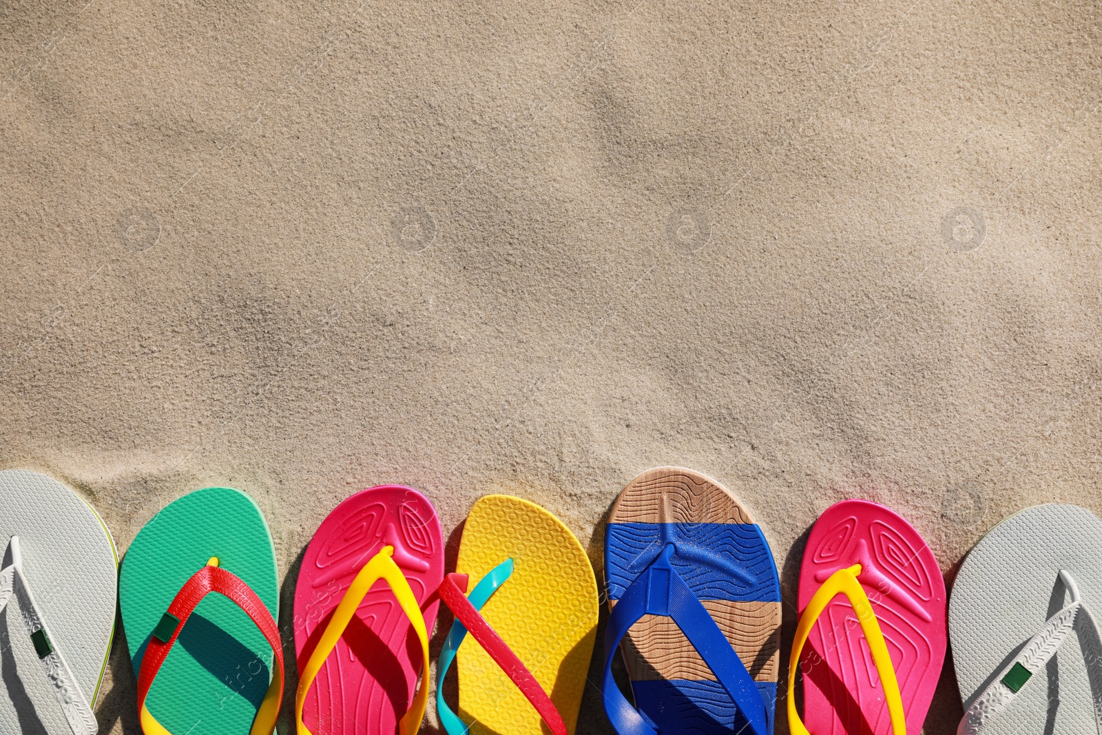 Photo of Stylish flip flops on beach, flat lay. Space for text