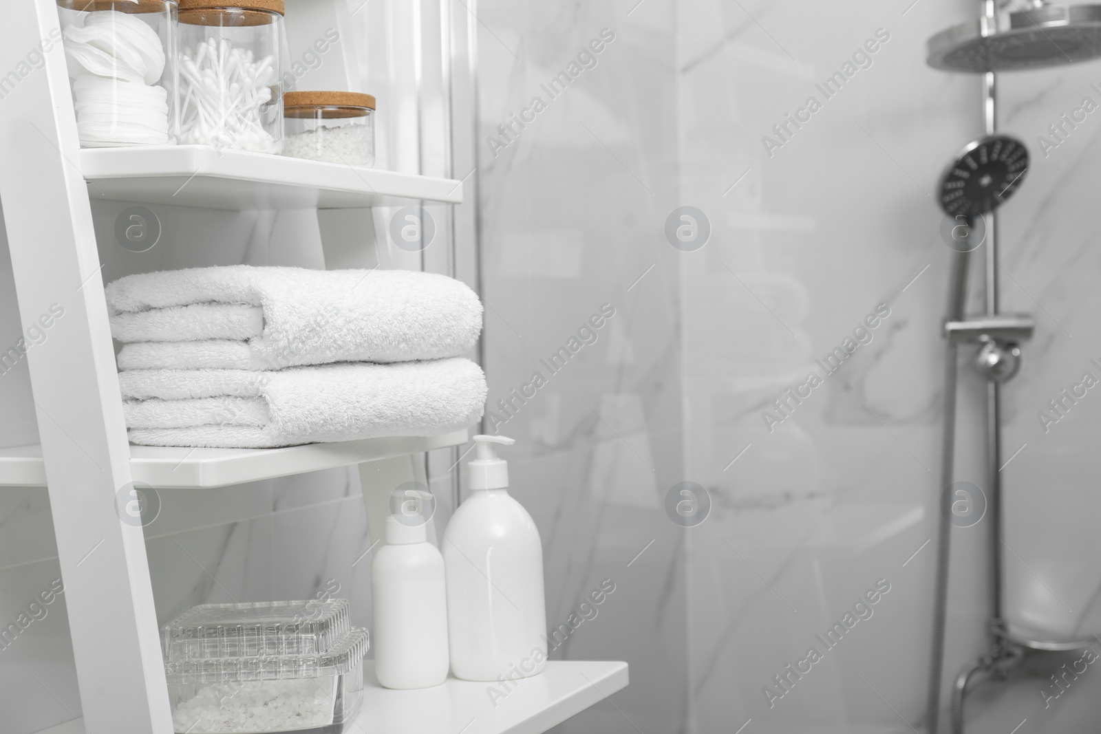 Photo of Stacked bath towels on white shelf in bathroom, space for text