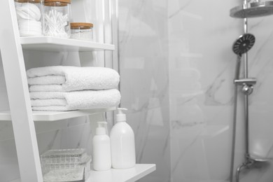 Stacked bath towels on white shelf in bathroom, space for text