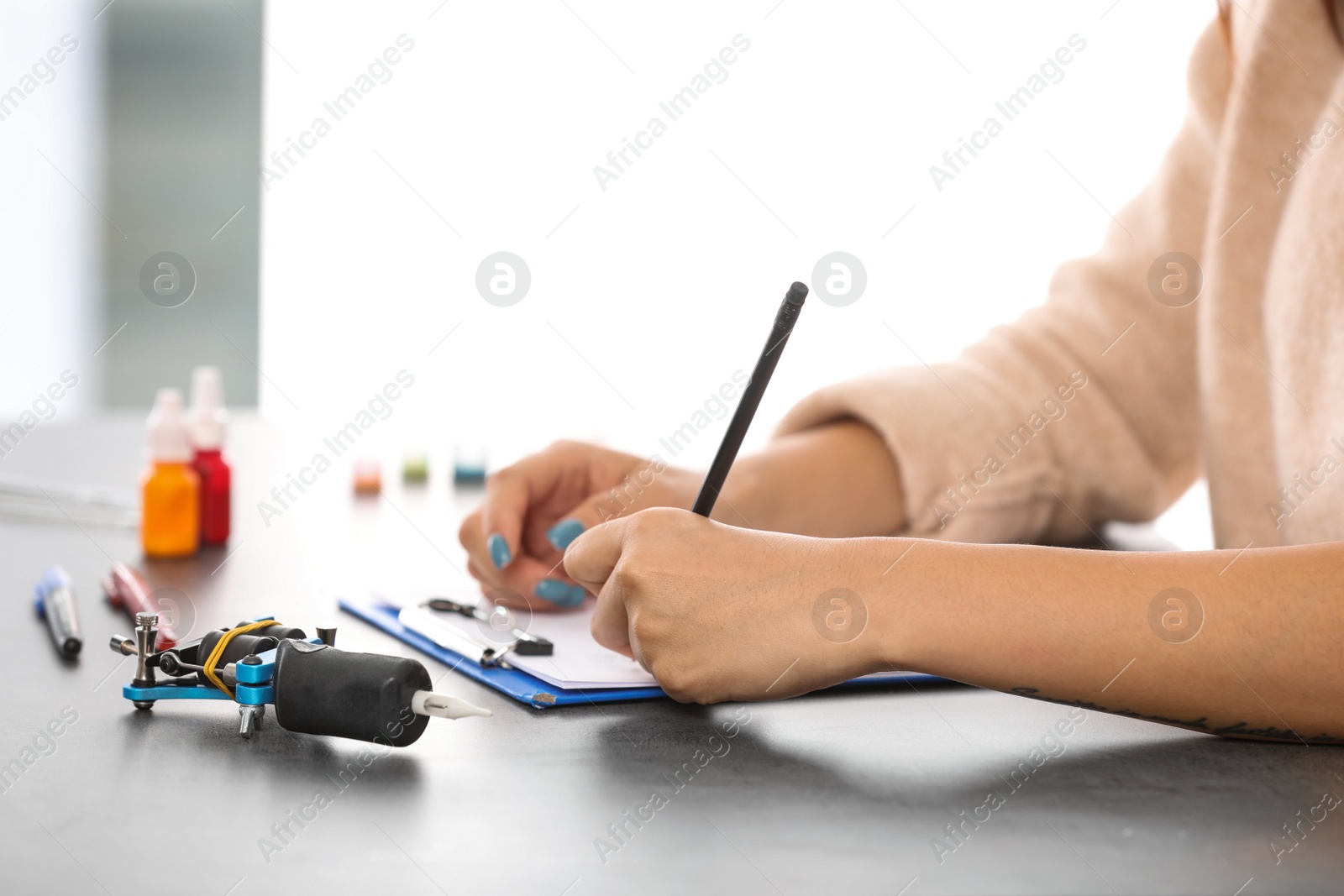 Photo of Professional tattoo artist drawing sketch at table indoors