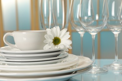 Set of clean dishware and flower on light blue table, closeup