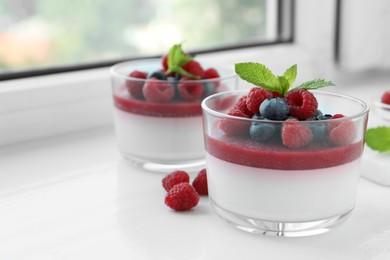 Photo of Delicious panna cotta with berries on window sill