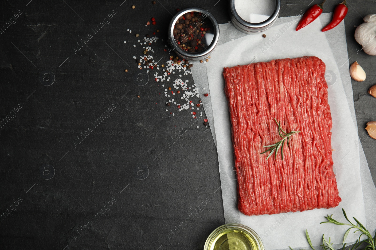 Photo of Raw fresh minced meat and other ingredients on black table, flat lay. Space for text