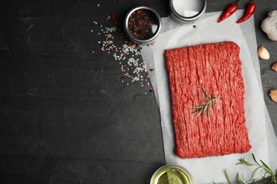 Raw fresh minced meat and other ingredients on black table, flat lay. Space for text