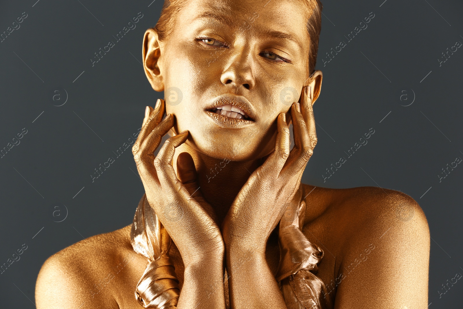 Photo of Portrait of beautiful lady with gold paint on skin against grey background, closeup