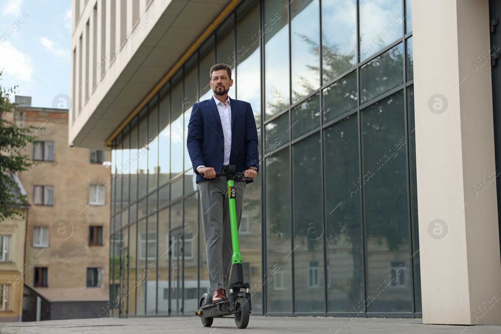 Photo of Businessman riding modern kick scooter on city street, space for text