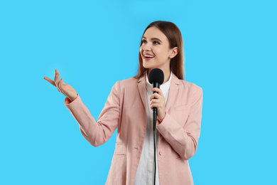 Photo of Young female journalist with microphone on blue background