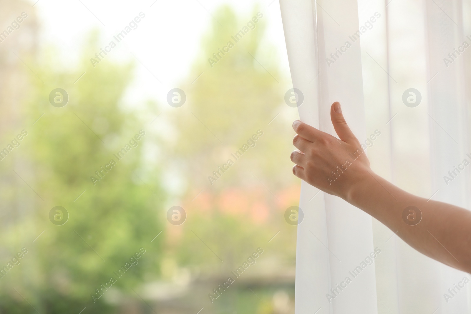 Photo of Woman opening curtain indoors, closeup. Space for text