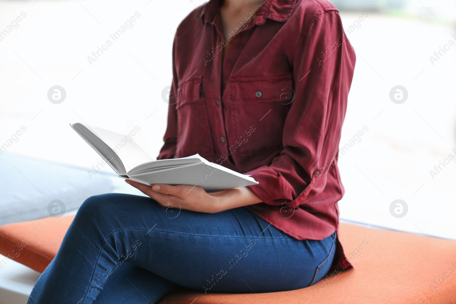 Photo of Young woman reading book in library, closeup