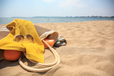 Photo of Beach bag, sunglasses and other accessories on sand near sea. Space for text