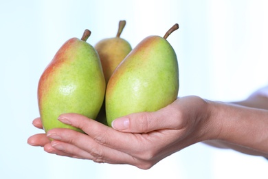 Photo of Woman holding fresh ripe pears against light background, closeup
