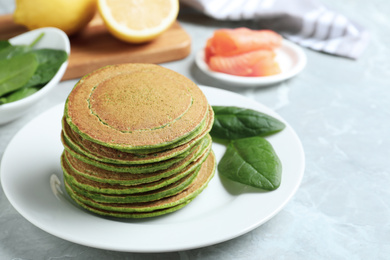 Photo of Tasty spinach pancakes on light grey marble table, closeup