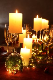 Photo of Christmas celebration. Burning candles, glasses and festive decor on table