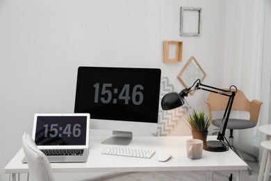 Stylish workplace with computers on table in room