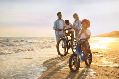 Photo of Happy family with bicycles on sandy beach near sea