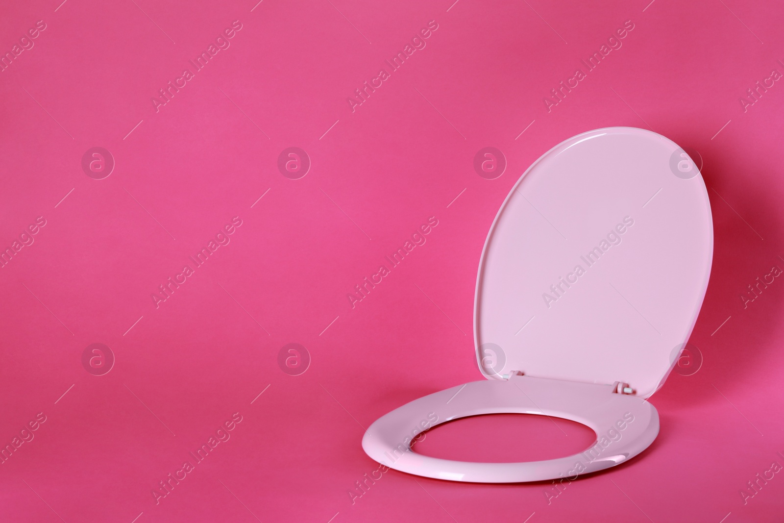 Photo of New plastic toilet seat on pink background, space for text