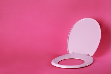 Photo of New plastic toilet seat on pink background, space for text