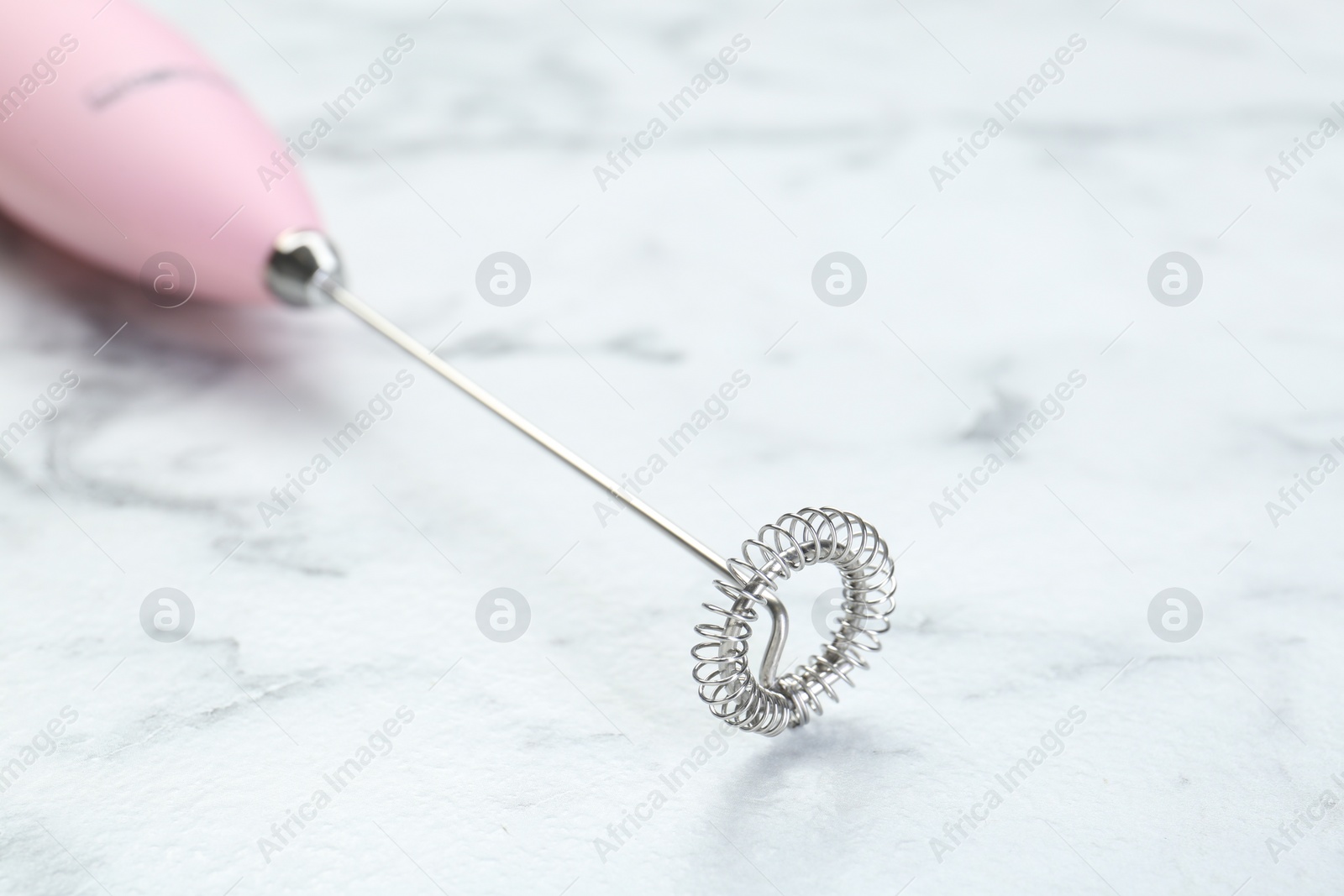 Photo of Pink milk frother wand on white marble table, closeup