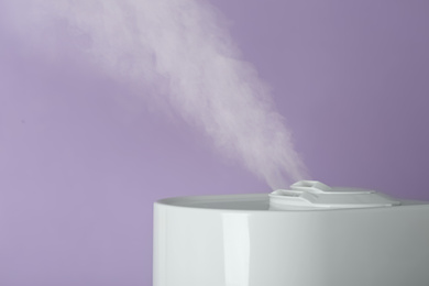 Photo of Modern air humidifier on violet background, closeup. Space for text
