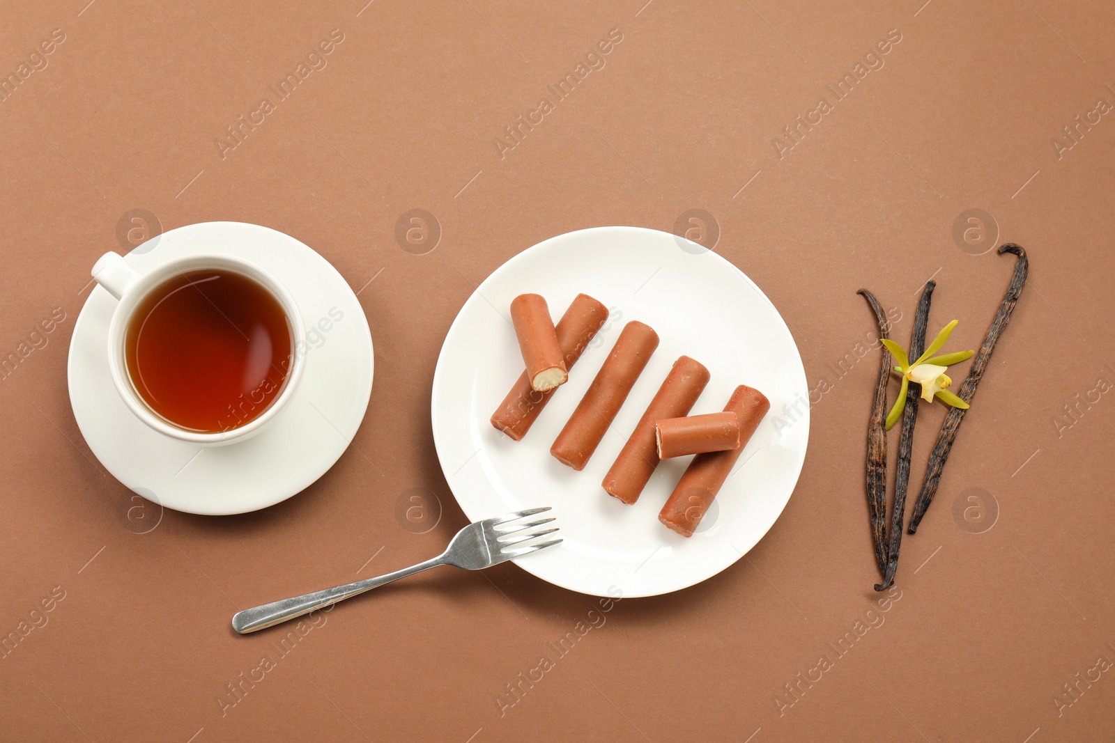 Photo of Glazed curd cheese bars, vanilla pods and tea on light brown background, flat lay