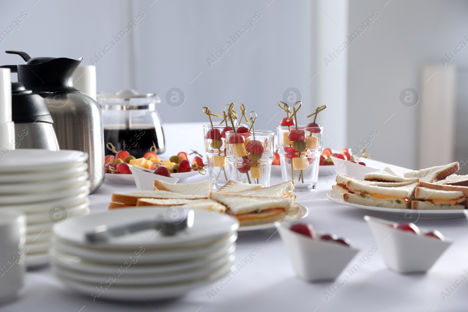 Photo of Table with different delicious snacks and dishware indoors. Coffee break