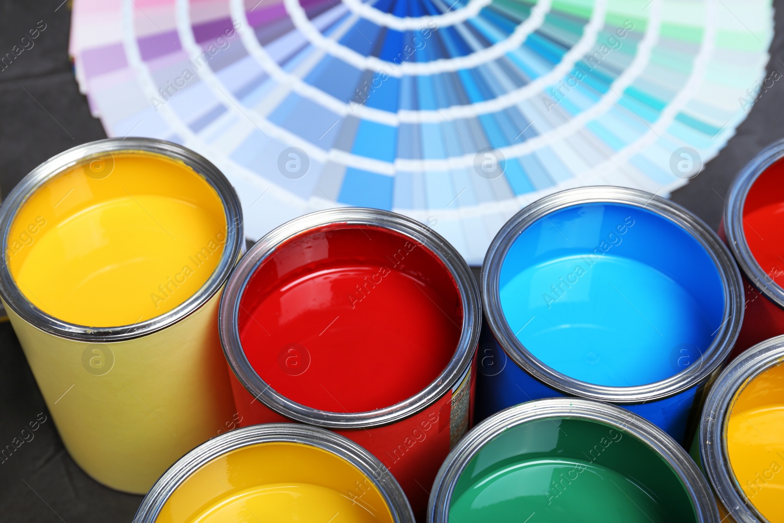 Photo of Paint cans and color palette samples on table, closeup