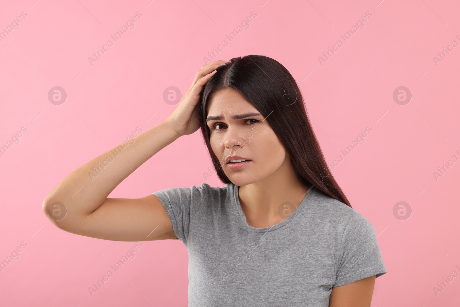 Photo of Emotional woman examining her hair and scalp on pink background