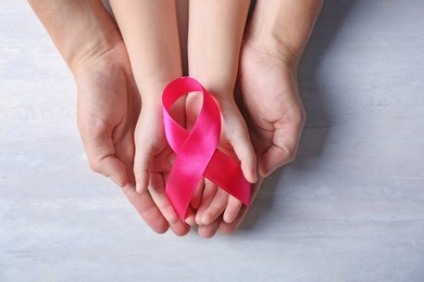 Photo of Woman and girl holding pink ribbon on grey background, top view. Breast cancer awareness