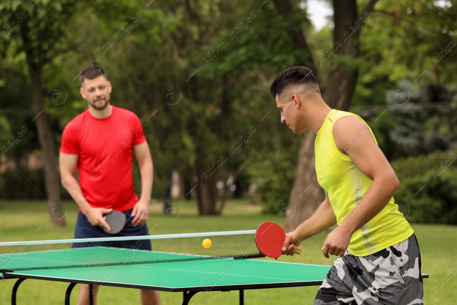 Photo of Friends playing ping pong outdoors on summer day