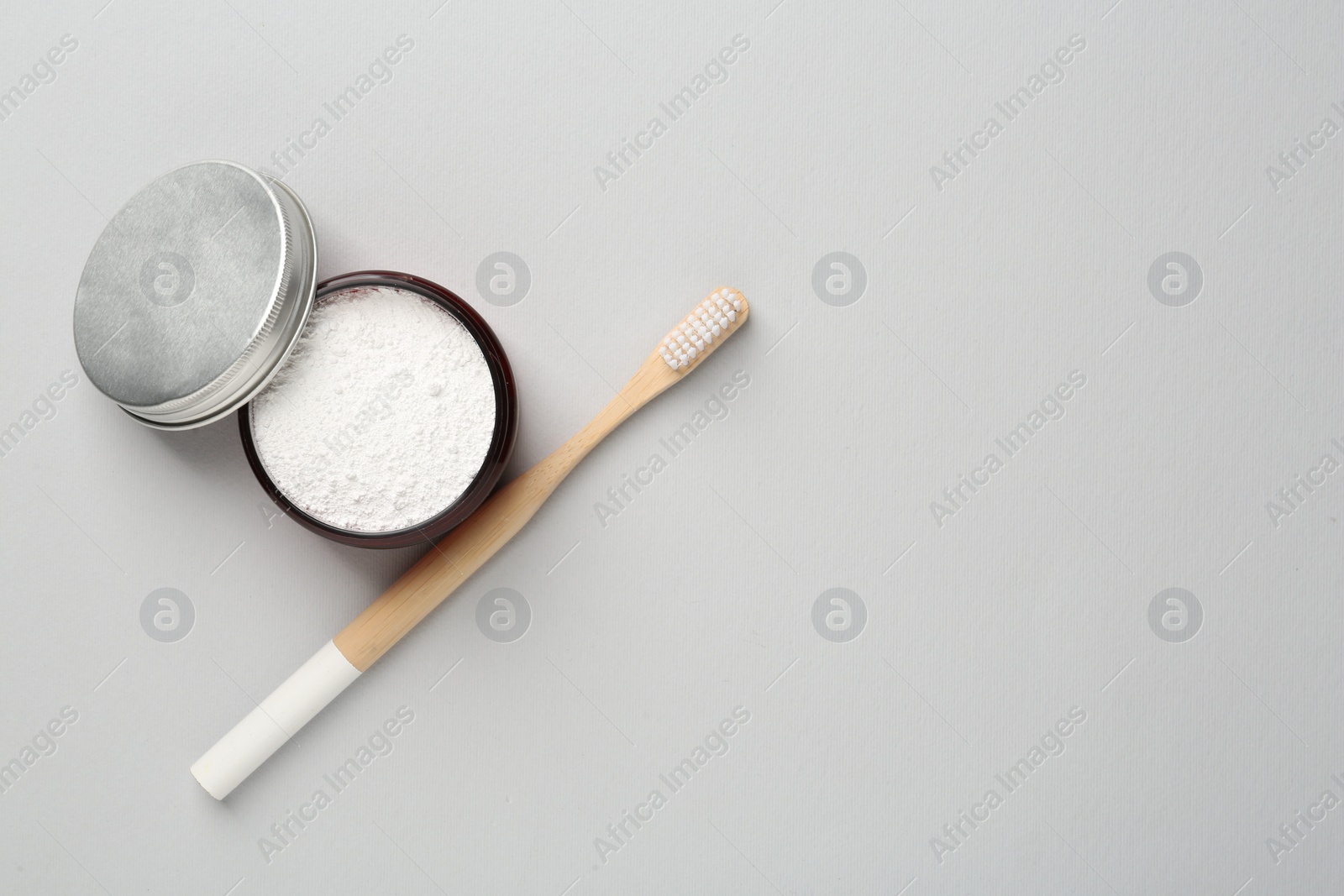 Photo of Jar of tooth powder and brush on light grey background, flat lay. Space for text