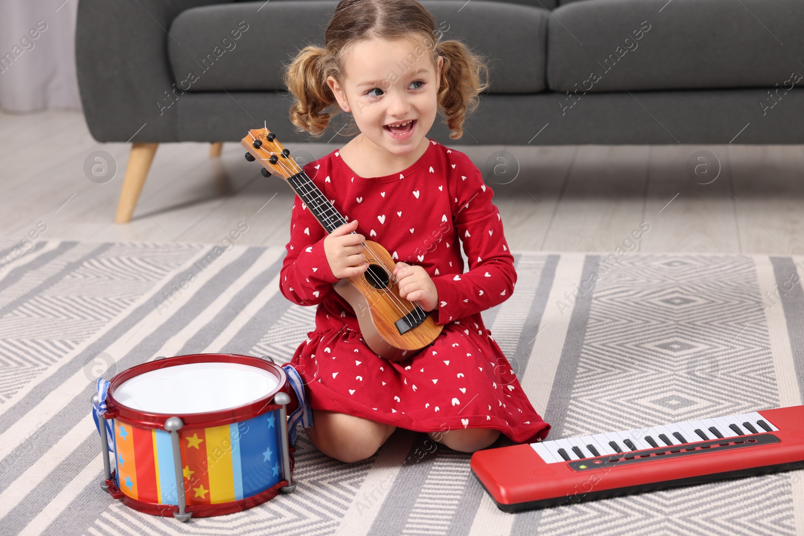 Photo of Little girl playing toy guitar at home