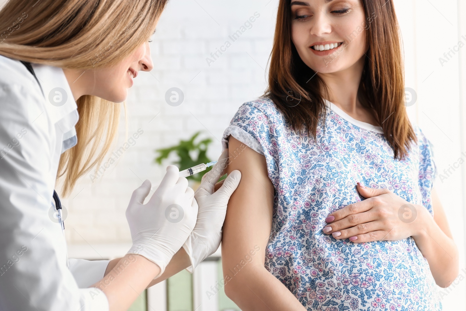 Photo of Doctor vaccinating pregnant woman in clinic