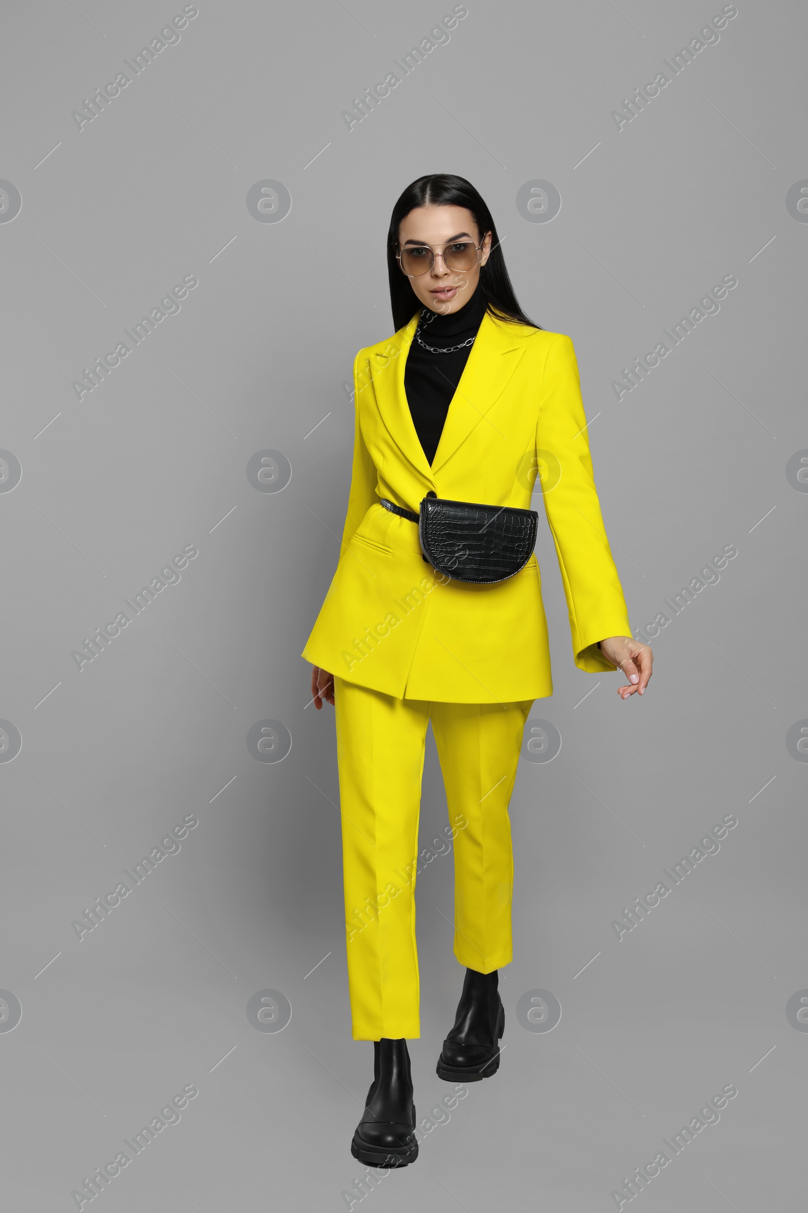 Photo of Beautiful young woman with stylish waist bag on grey background