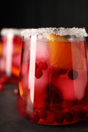 Photo of Tasty cranberry cocktail with ice cubes in glass on dark gray table, closeup